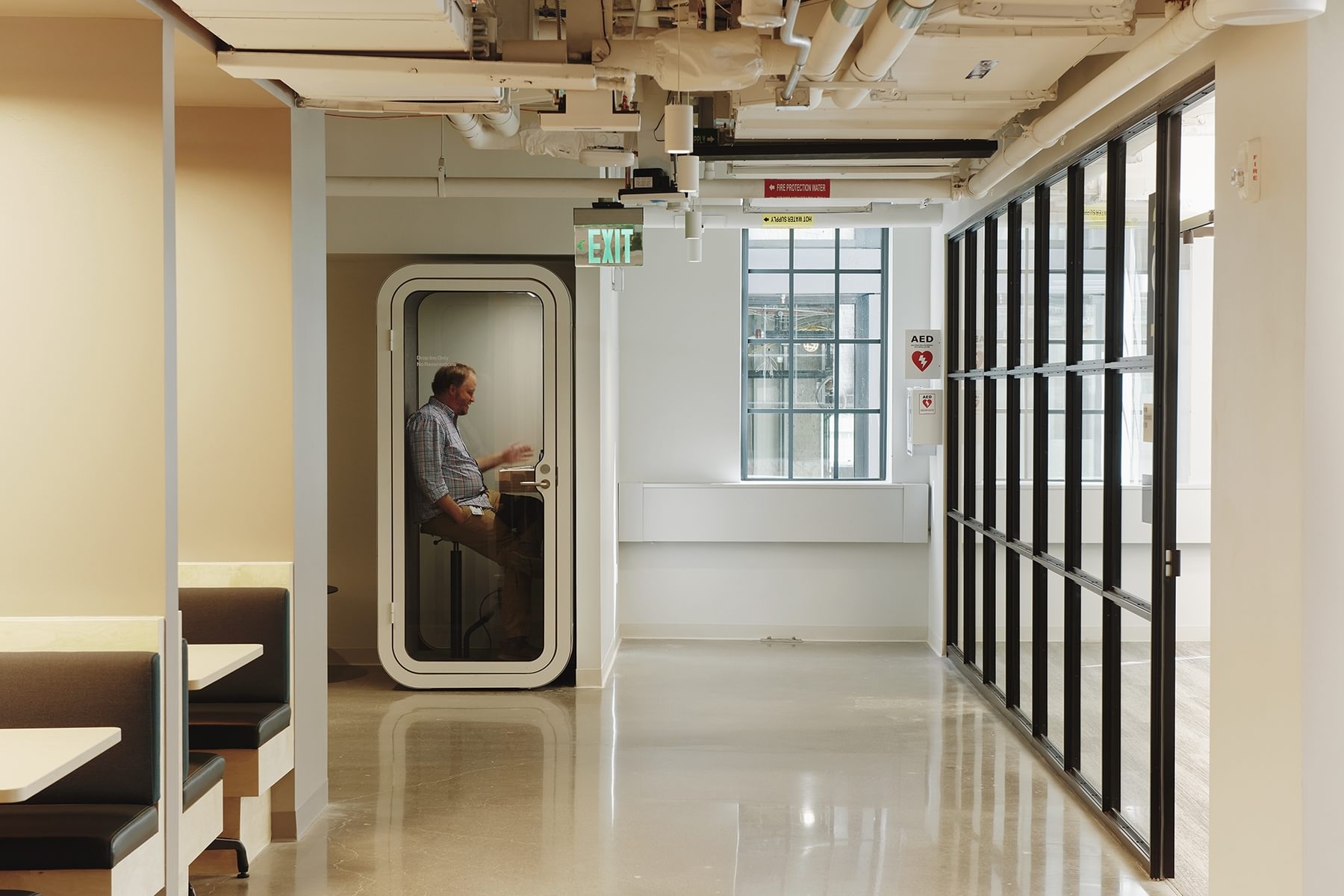 A man takes a meeting in the quiet solitude of a phone booth at The Engine.