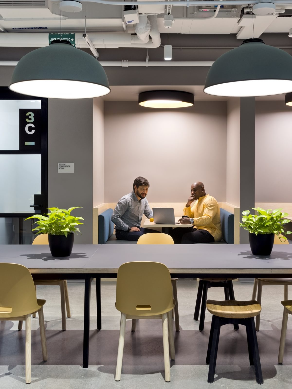 Two residents look at a laptop in a shared workspace on the third floor at The Engine.