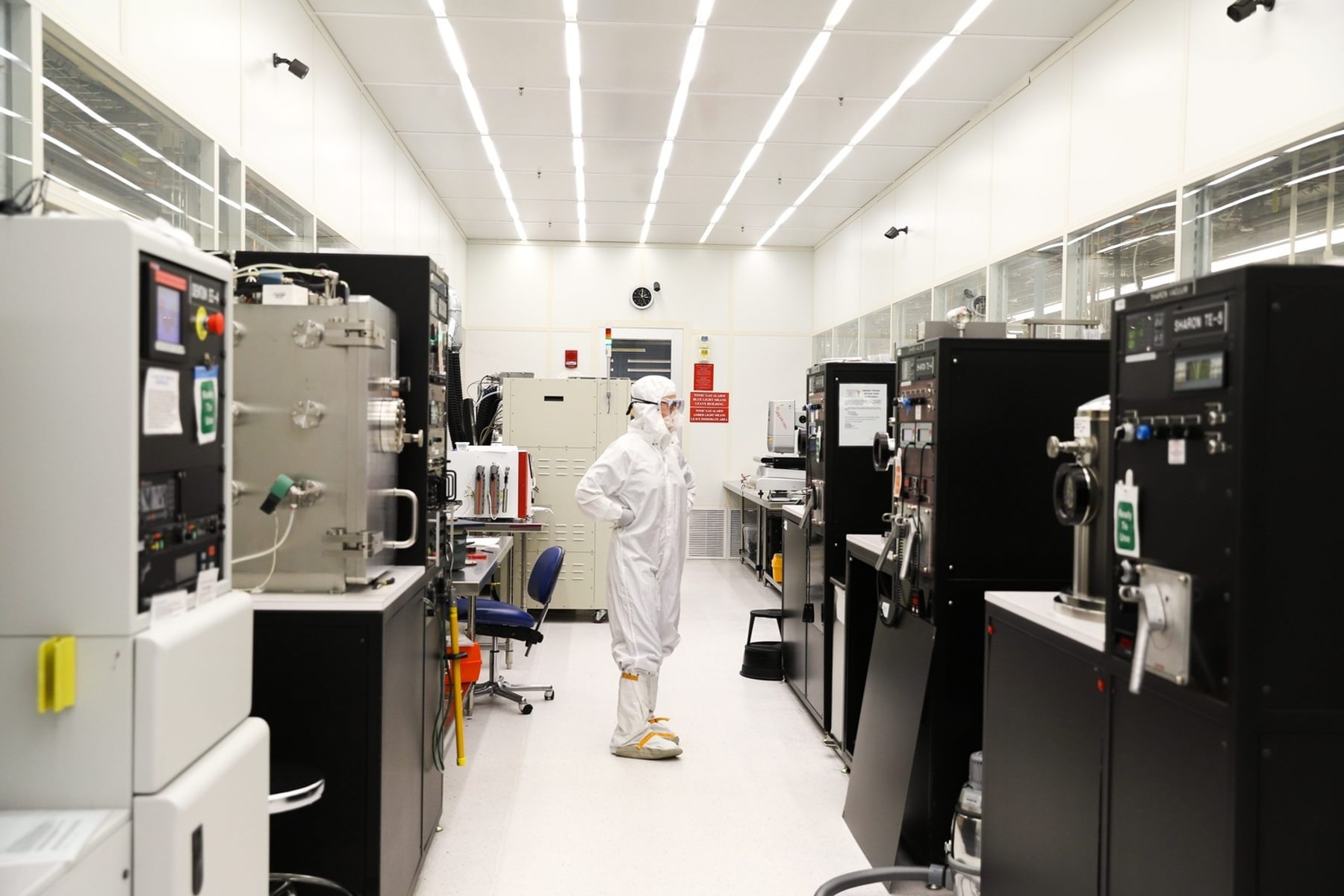 An engineer wearing personal protective equipment stands amidst large machines at Harvard's Center for Nanoscale Systems.